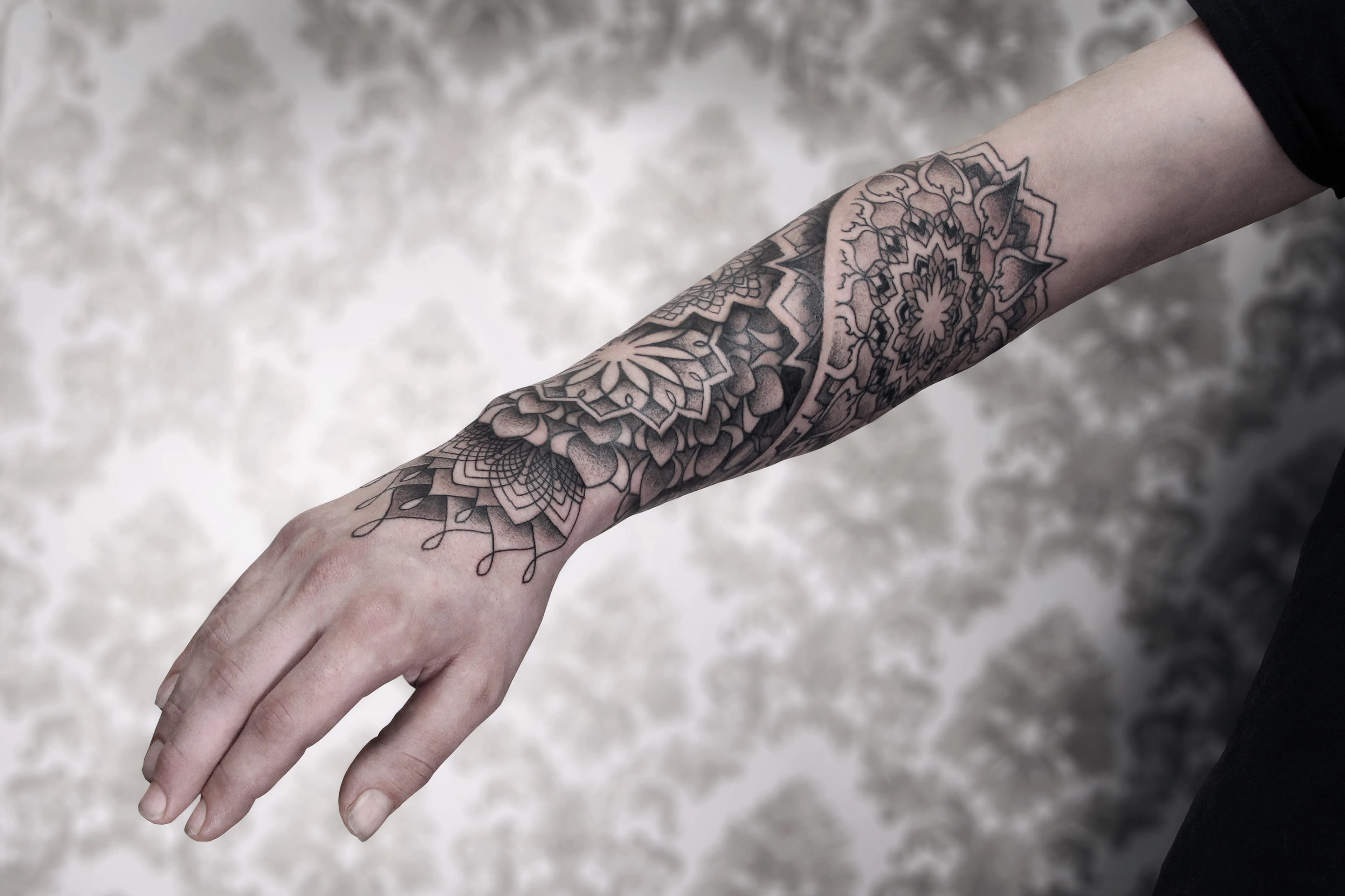 Arm with intricate DotsToLines mandala tattoo.